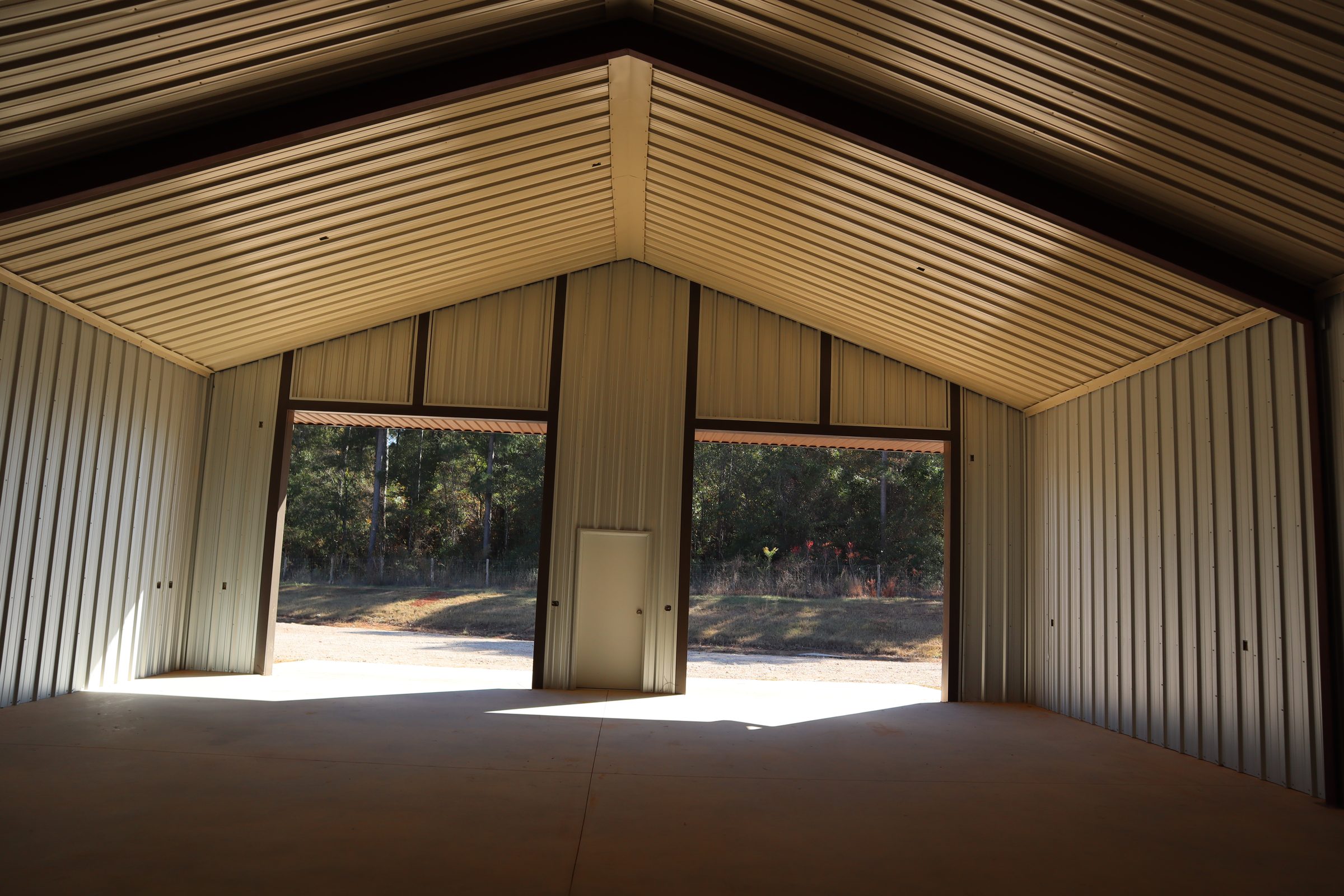 Interior view of a steel building roof showing panel seams and trim along the purlins